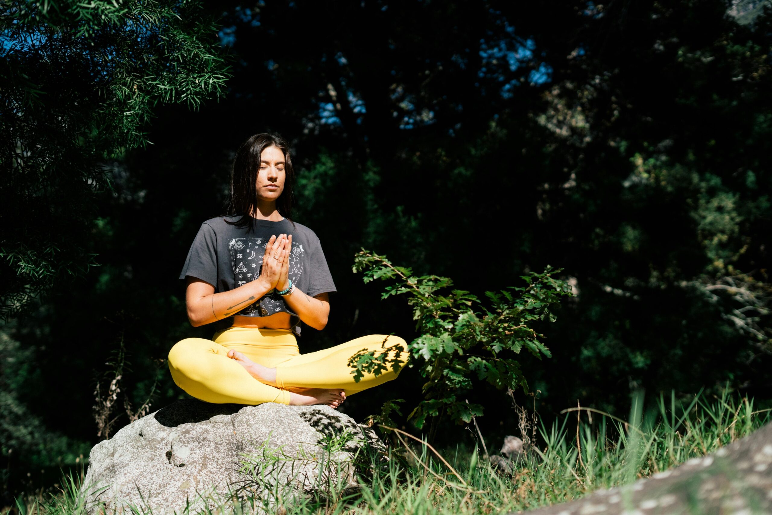 Woman sitting cross-legged outdoors practicing mindfulness meditation