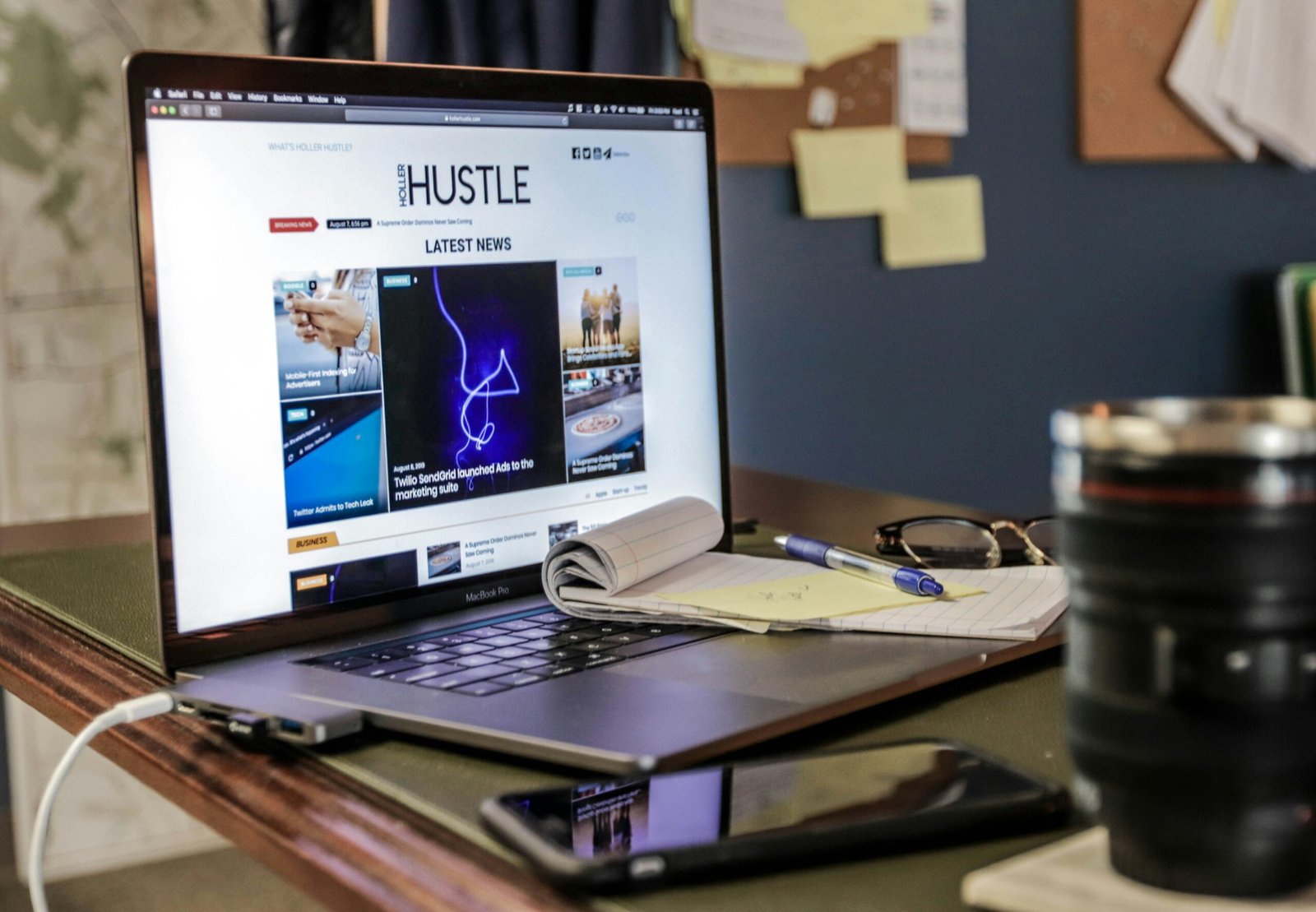 A person overwhelmed at their desk surrounded by papers and devices.