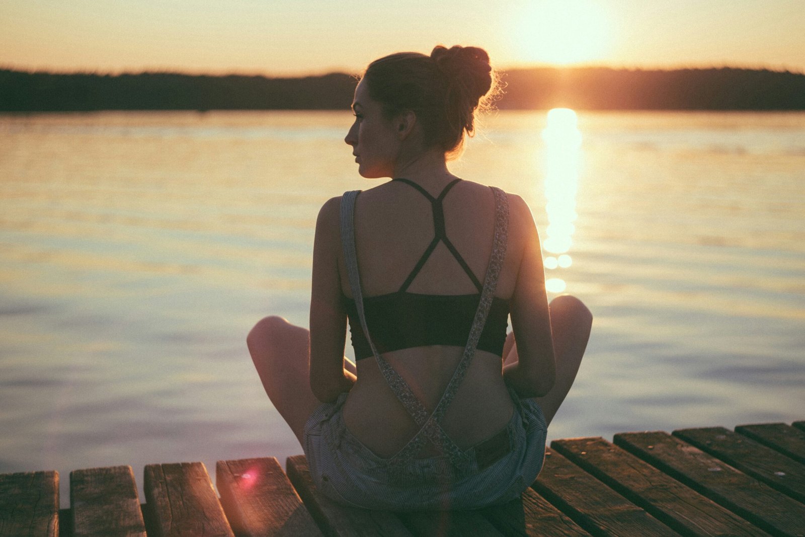 Woman meditating in front of sunrise