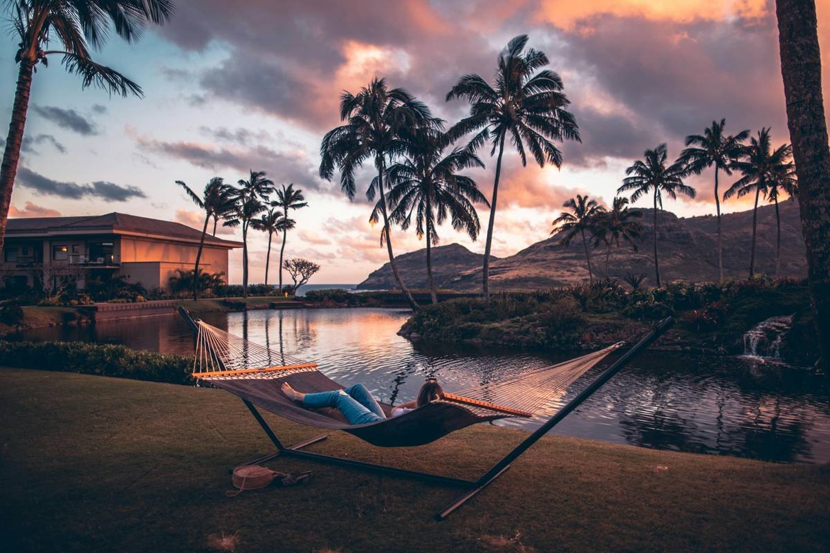 A person sitting cross-legged by a lake at sunset looking contemplative