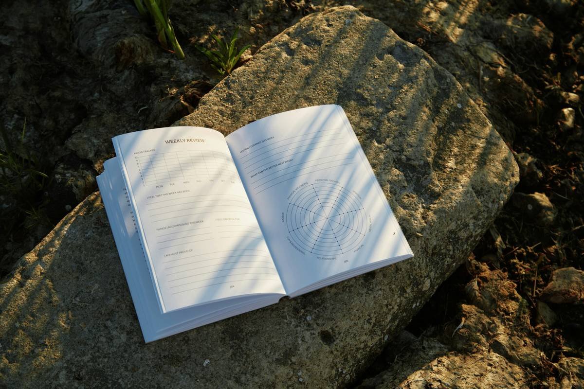 A woman meditating with a notebook on her lap under soft lighting.
