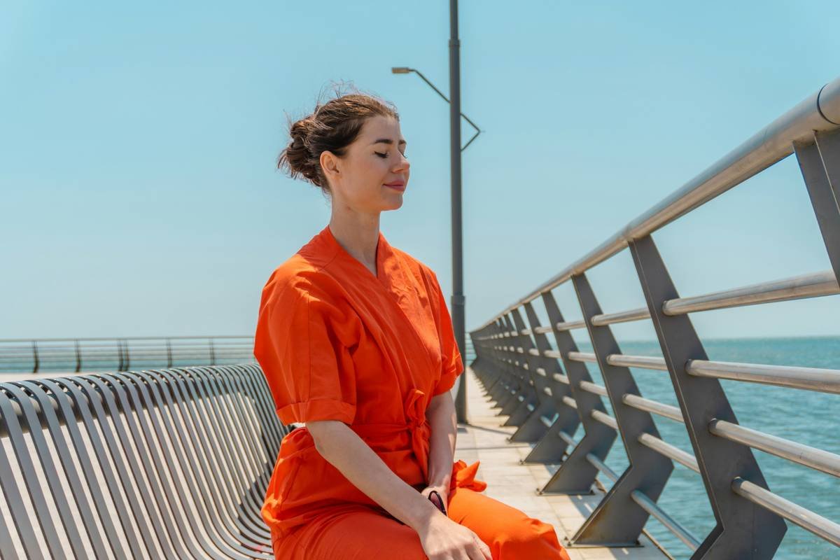 Woman sitting cross-legged outdoors practicing mindful breathing
